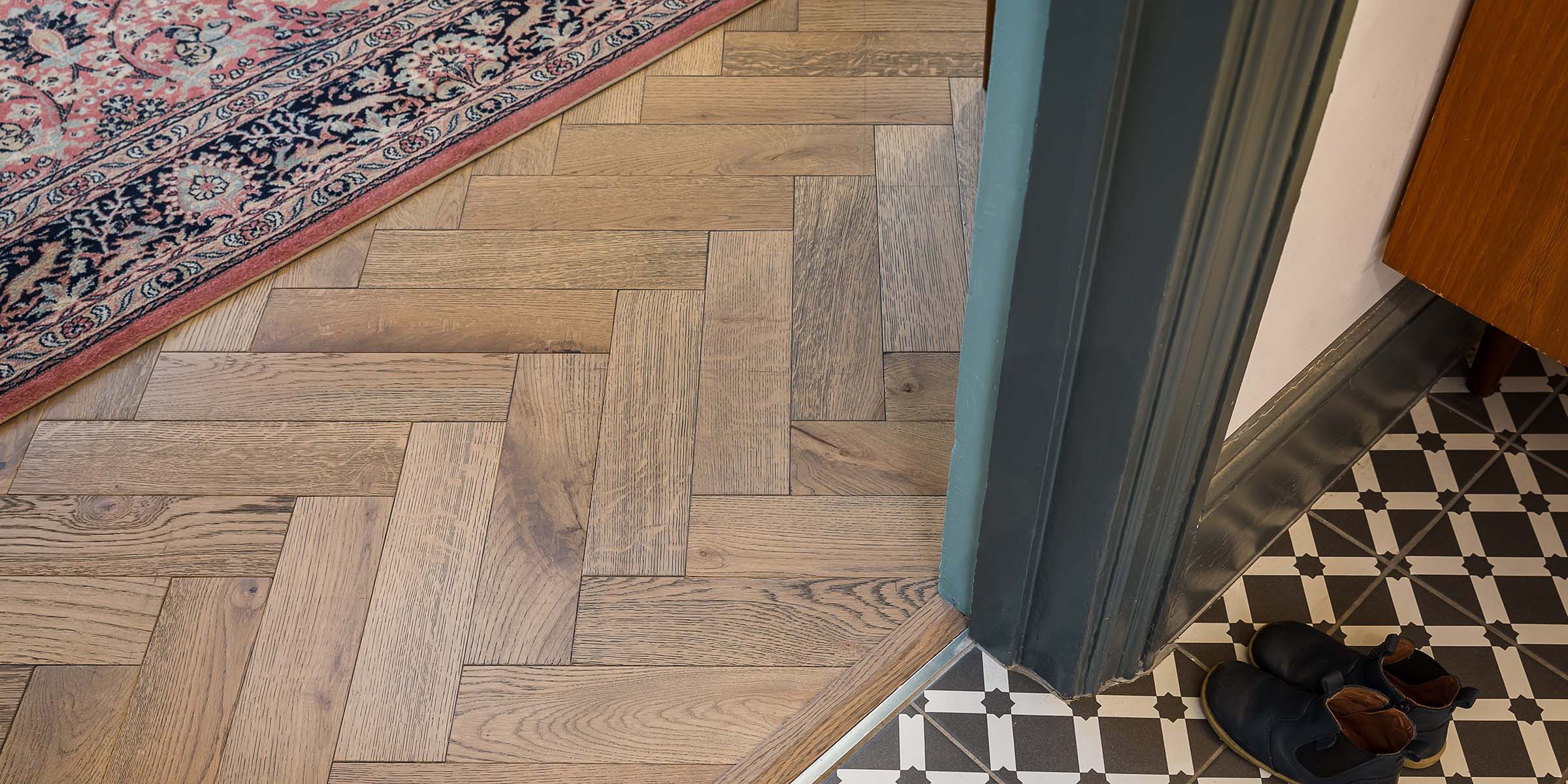 close up of herringbone wood floors with a mosaic tile