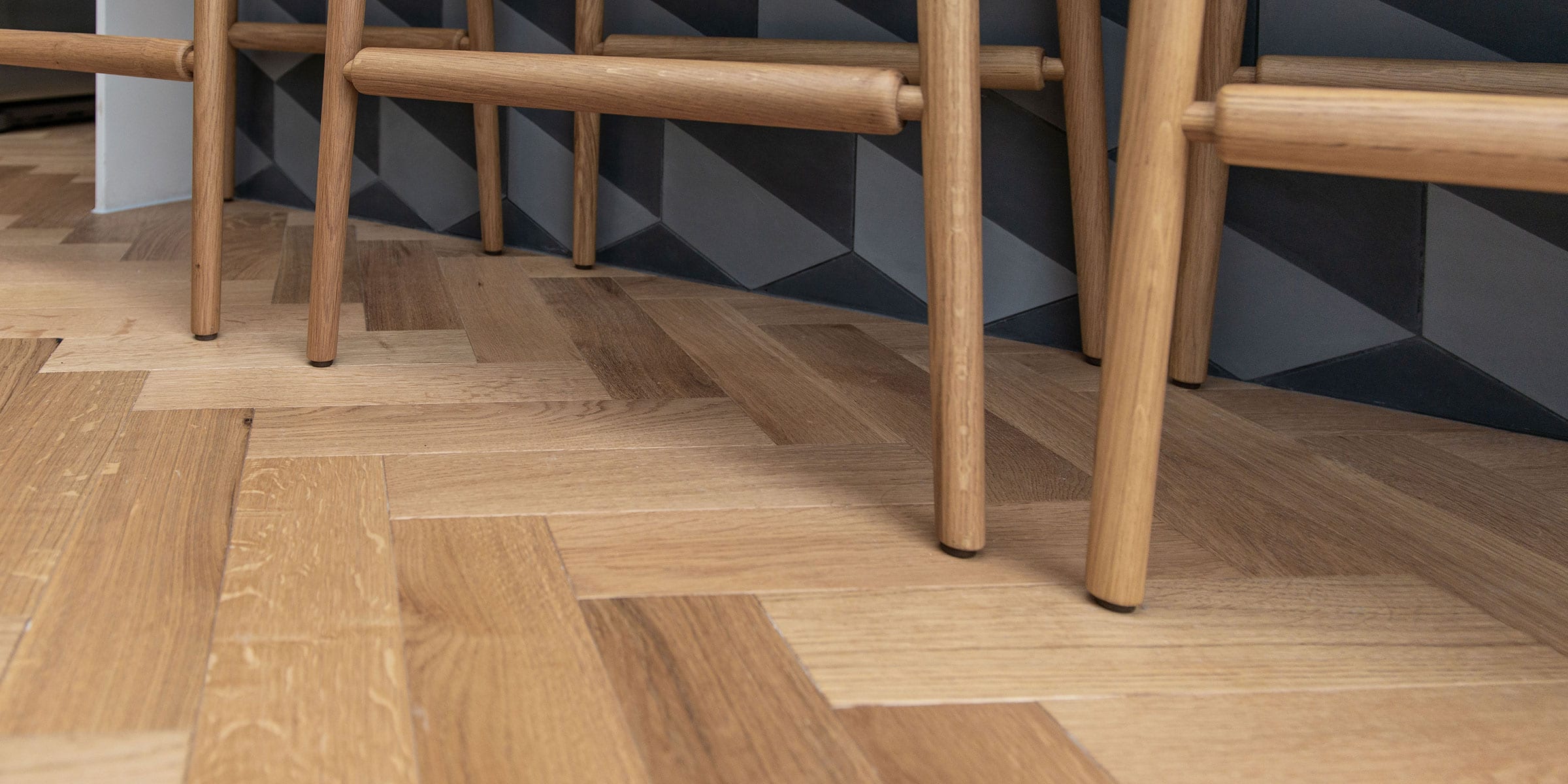 close up of herringbone wood flooring with wooden stools