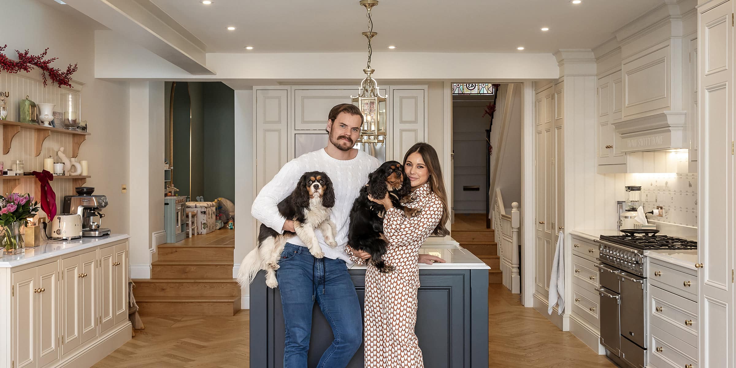 the couple holding two spaniels in a modern kitchen with wood floors