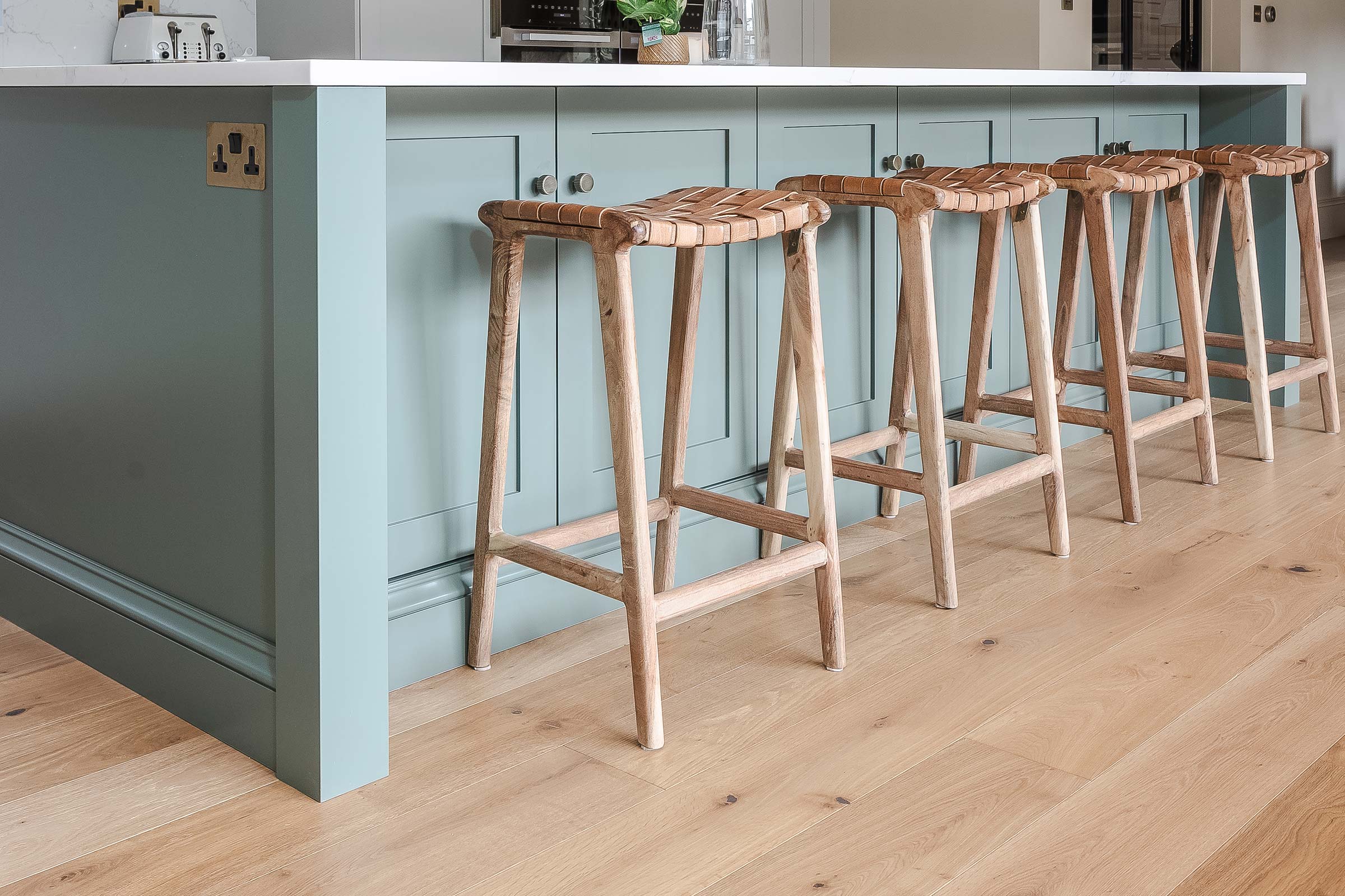 close up of teal wooden kitchen island with wooden bar stools and oak wood floors