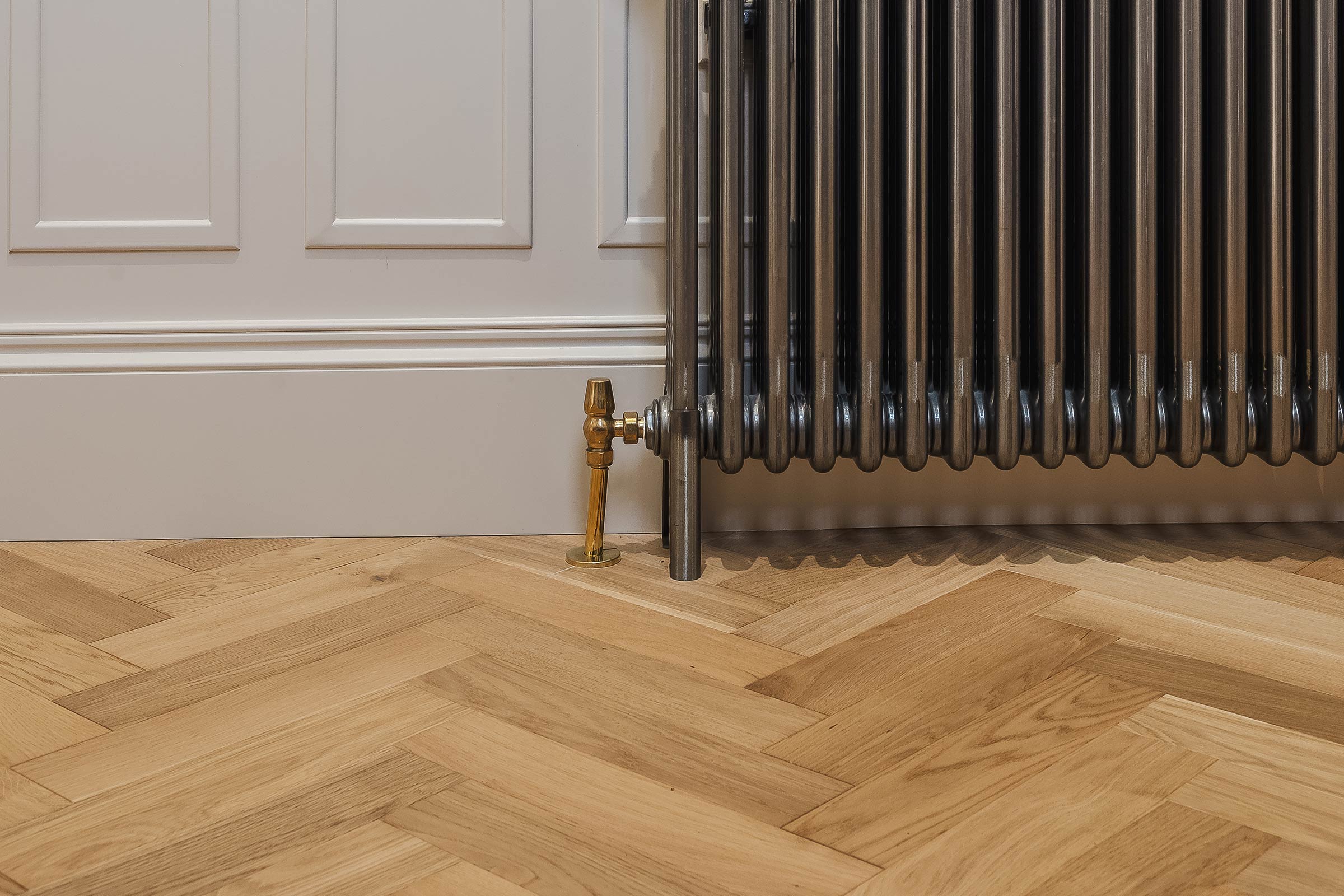 herringbone wood floors with a traditional radiator and white walls