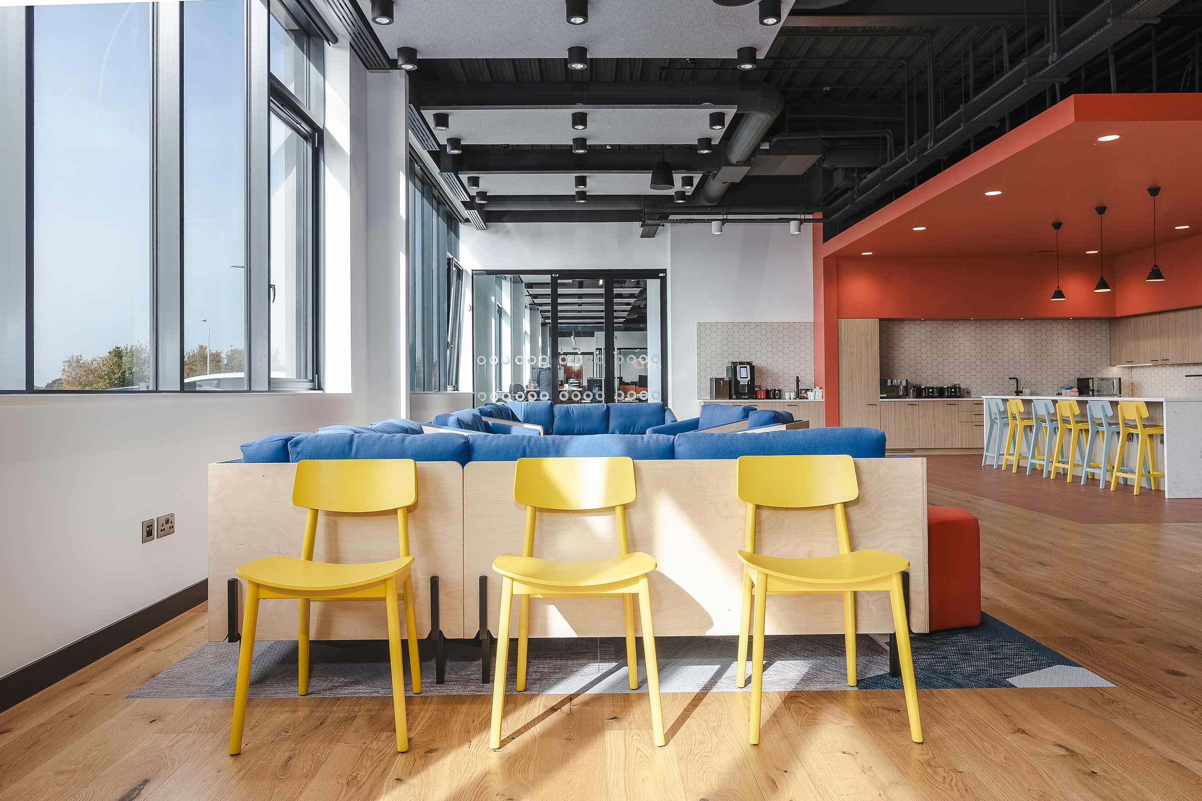 wooden floors in a large communal space with yellow chairs and orange and blue trim