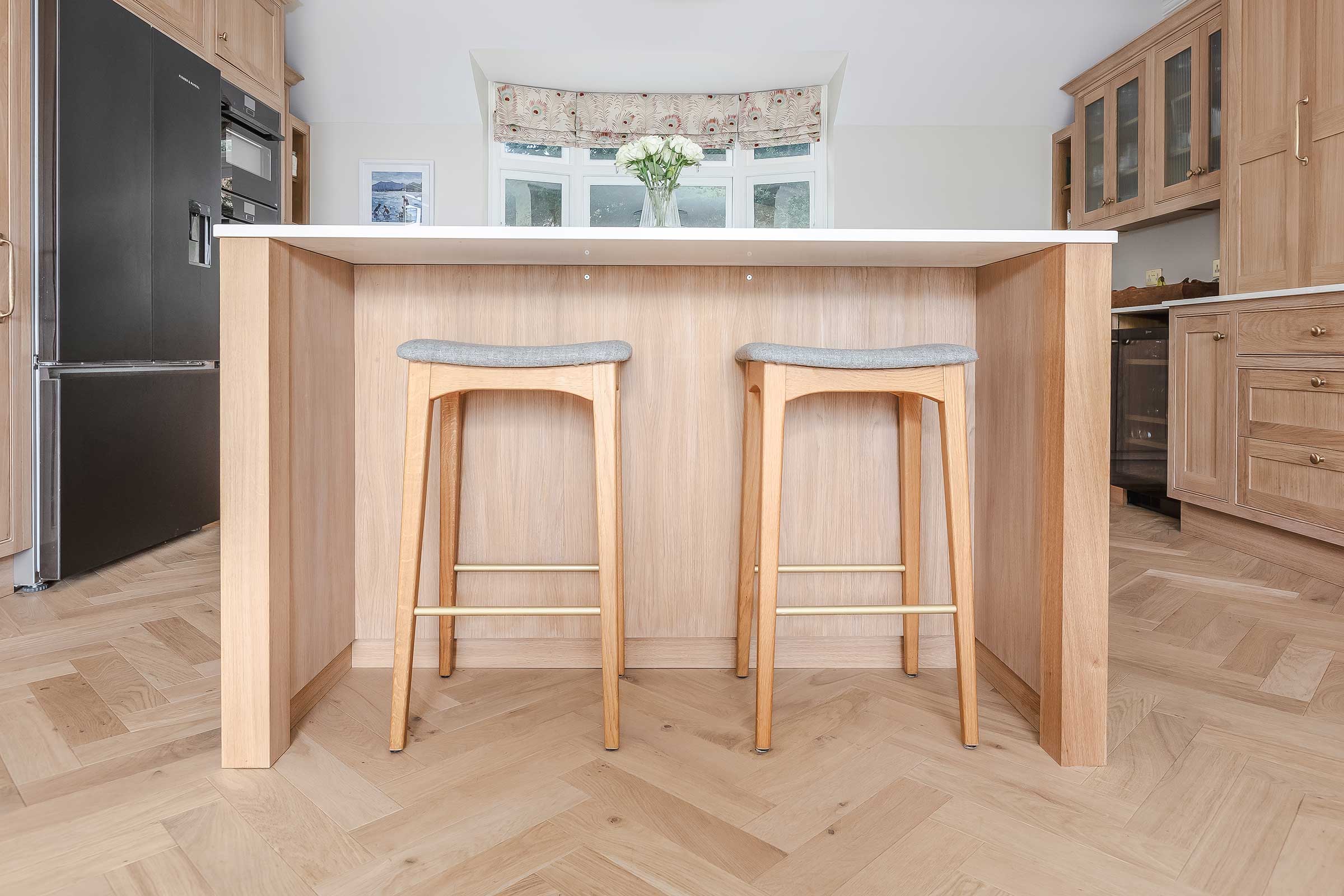 herringbone wood floors in a kitchen with wooden stools and an island