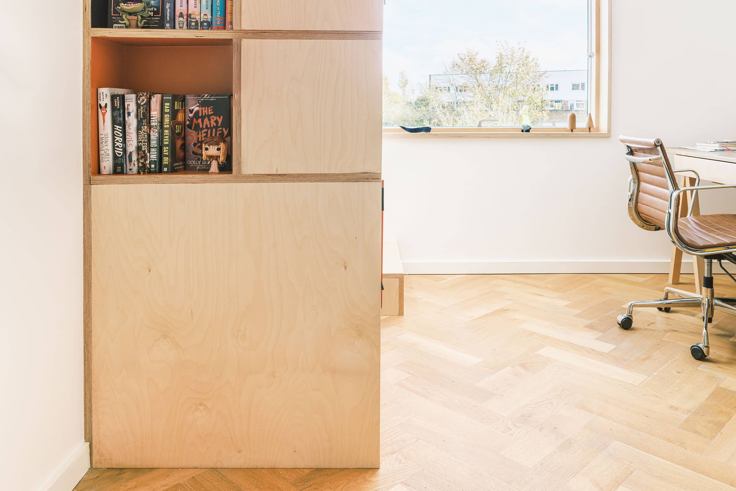 herringbone wood floors in a home office with a wooden cupboard and shelves