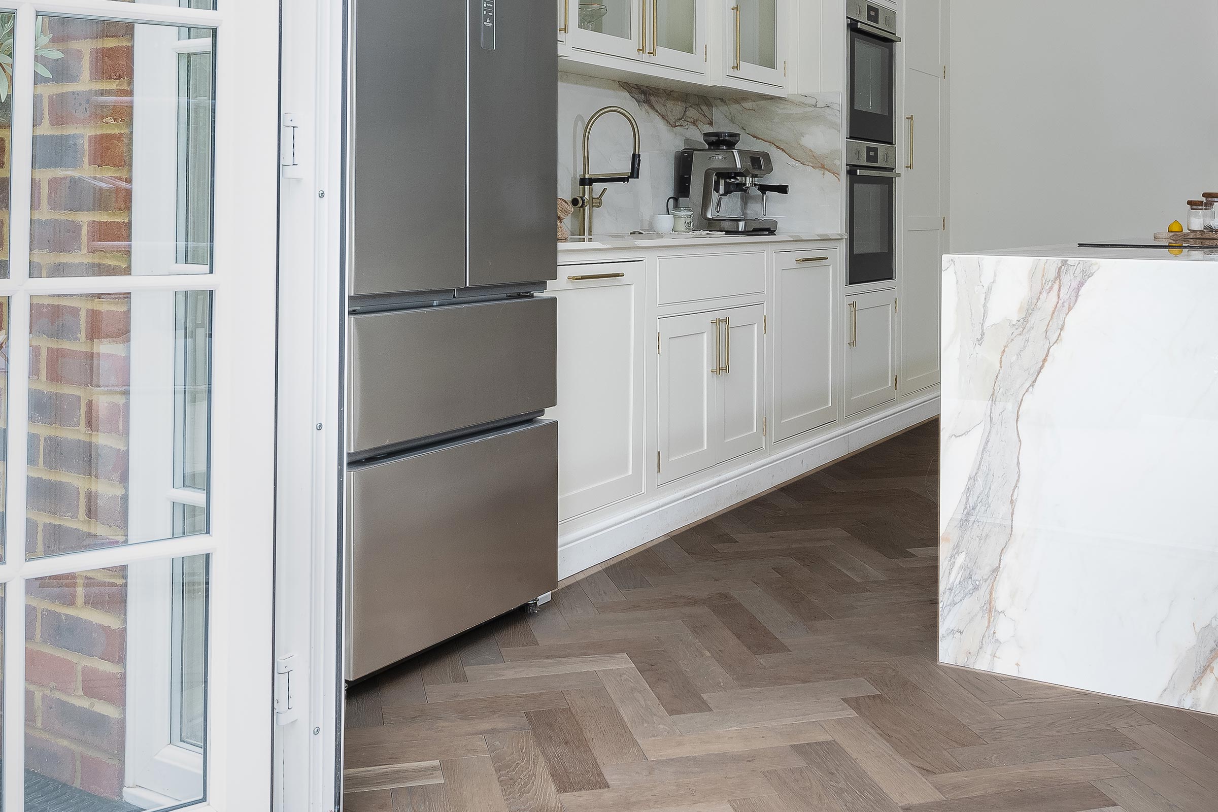 herringbone wood floors in a kitchen with white cupboards