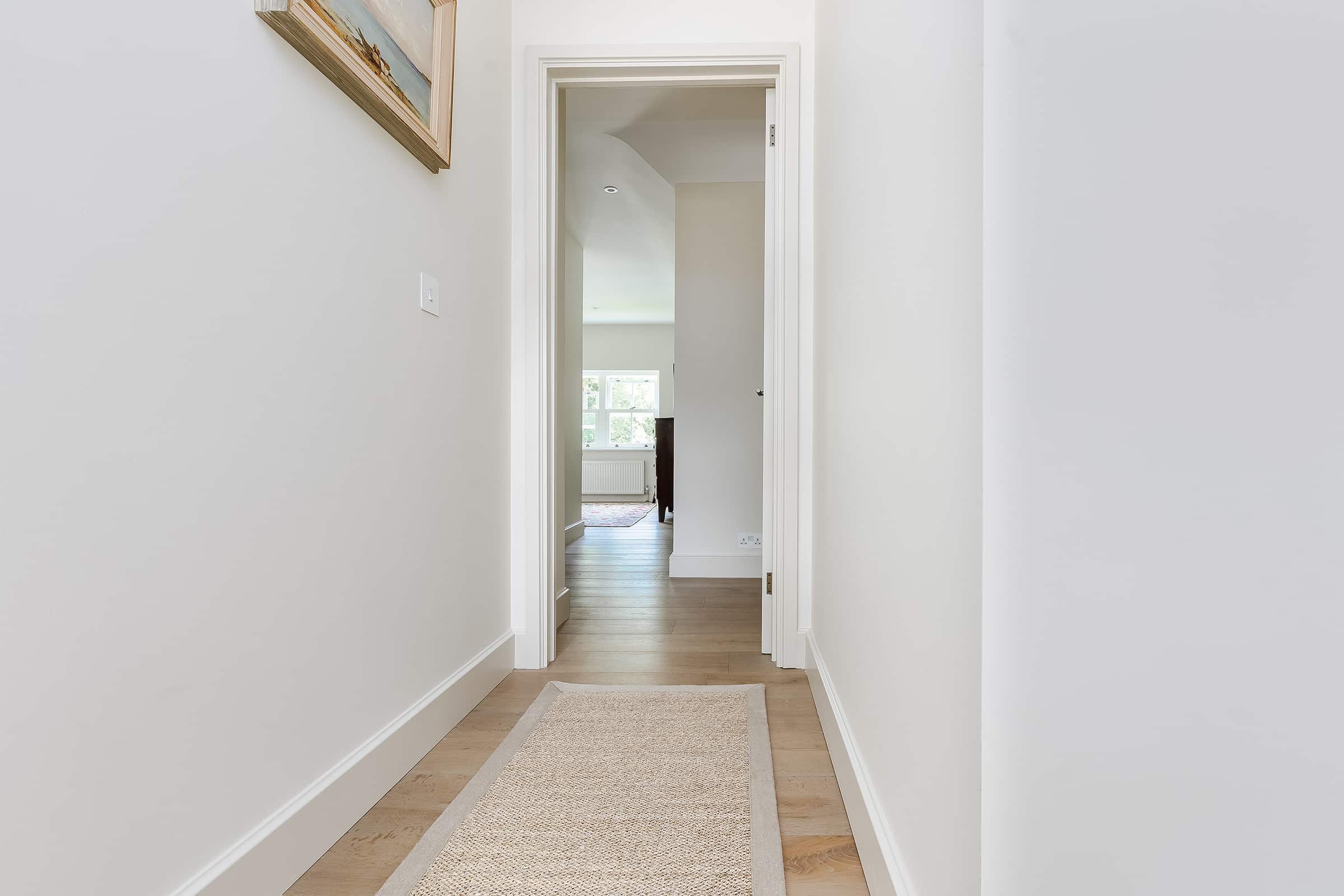 oak wood floors with a light runner and white walls