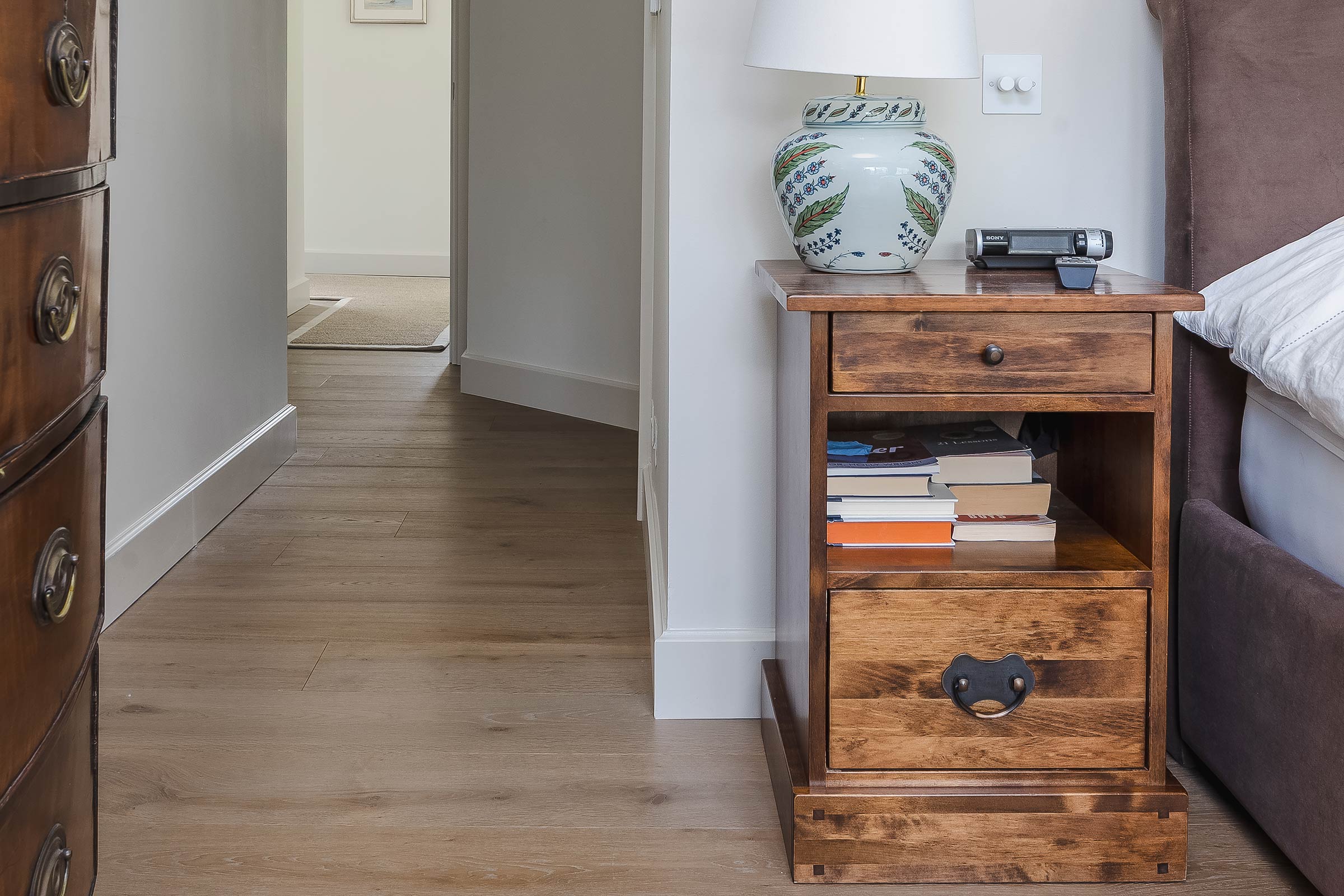 oak wood floors in a bedroom with a wooden bedside table and lamp