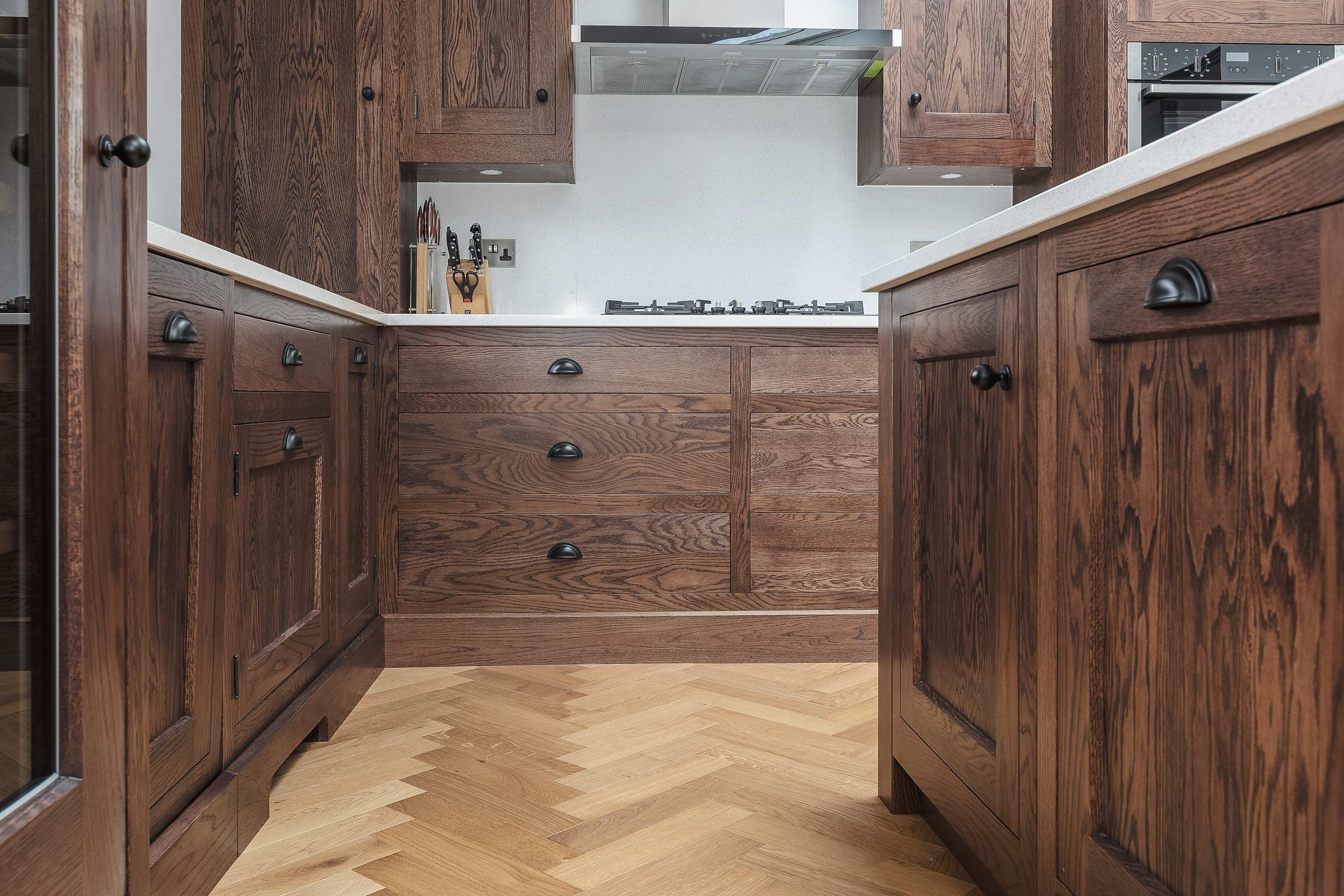 Herringbone floor in a kitchen with wooden cupboards and drawers