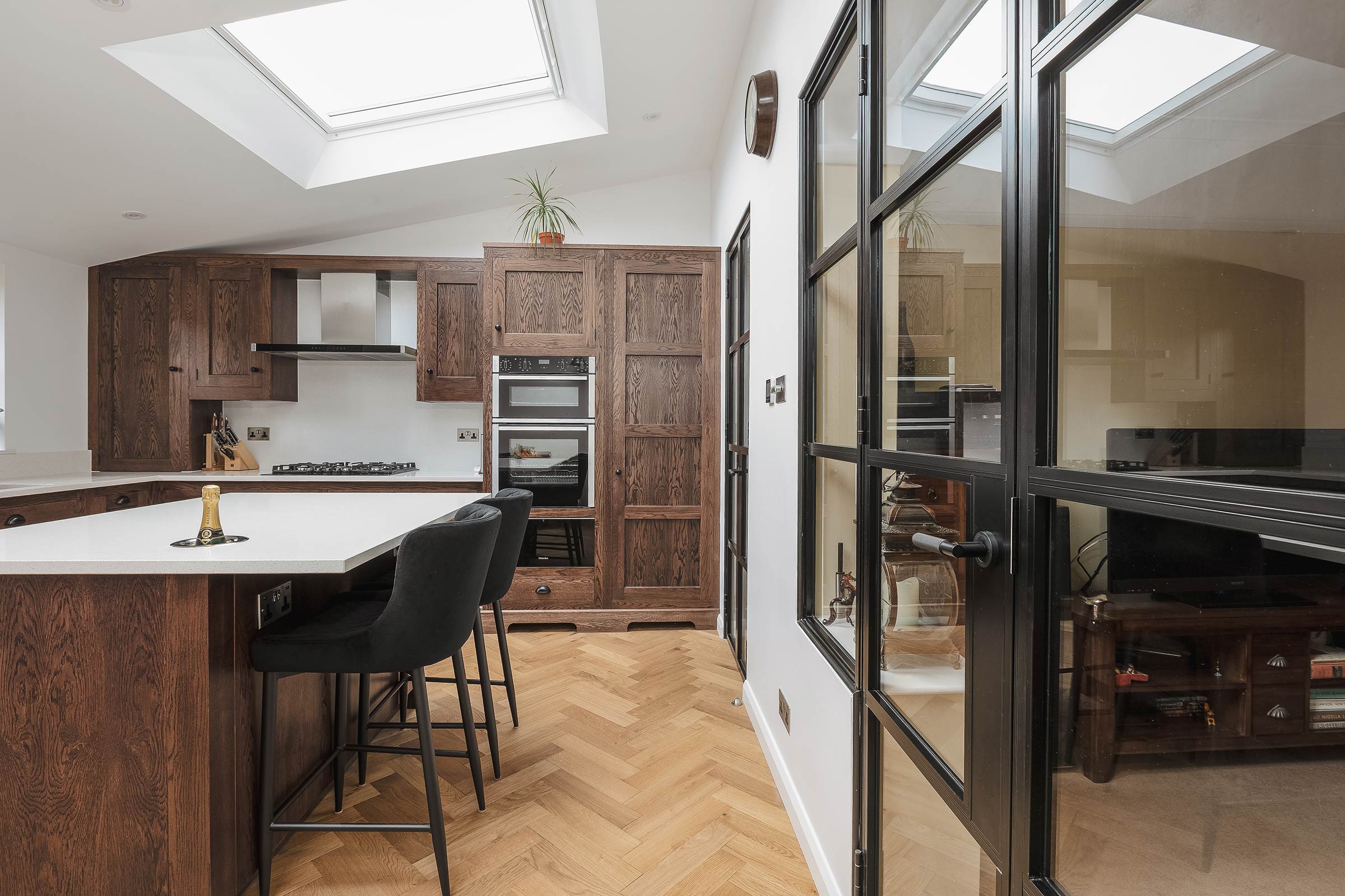 herringbone wood floors in a kitchen with a marble island and bar stools