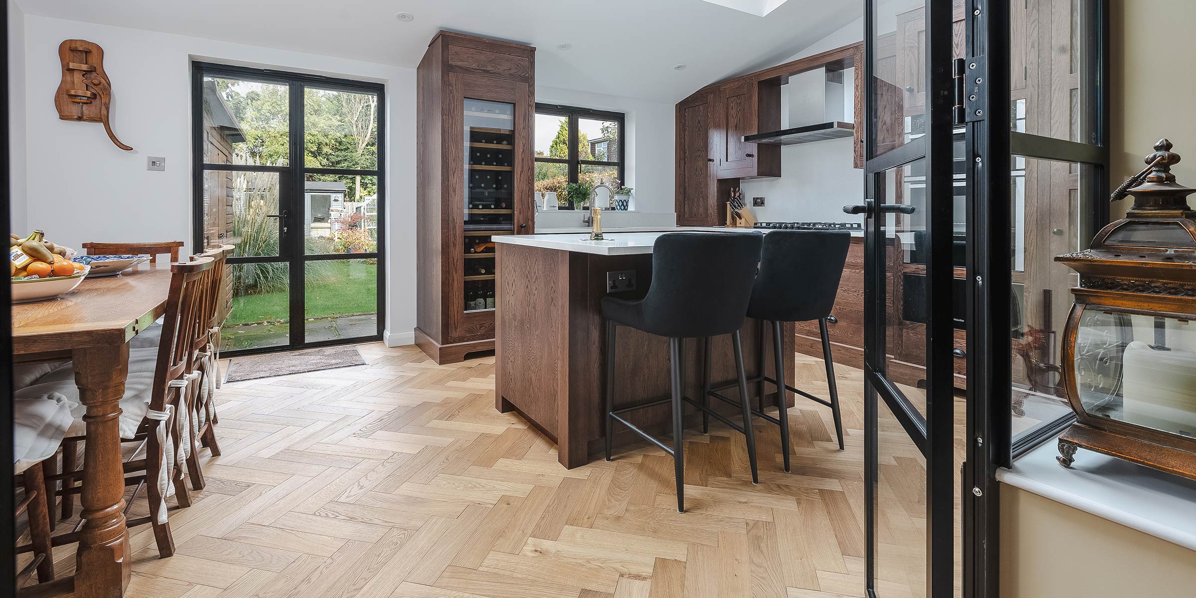 herringbone wood floors in a kitchen looking out over a back garden